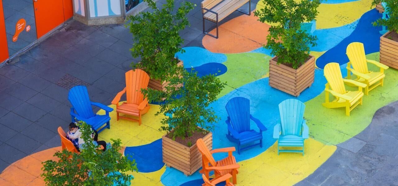 Header Bild Darmstädter Sommergarten – bunte Sitzmöbel, Bäume und Tische